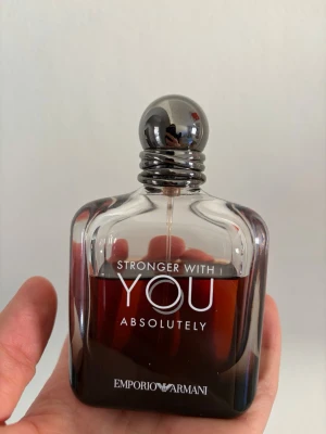 Emporio Armani Stronger With You Absolutely  - Emporio Armani Stronger With You Absolutely är en elegant parfym i en stilren, fyrkantig glasflaska med mörkbrun toning och silverfärgad rund kork. Doften är intensiv och modern, perfekt för dig som gillar exklusiva och trendiga parfymer. 100ml flaska mängd enligt bilder 