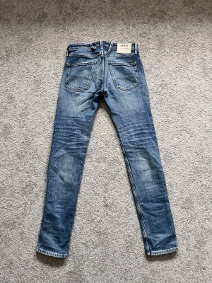 Replay Anbass - Säljer ett par klassiska blå skinny jeans från Levi's med fem fickor och snygga slitningar. Jeansen har en smal passform och är tillverkade i denim med lätt stretch. Perfekta för dig som gillar en tidlös och avslappnad stil. En av byxhällorna har lossnat (bild 3) men det går lätt att sy på. Skriv gärna vid minsta fundering!