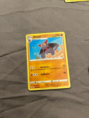 Pokémonkort Gliscor - Pokémonkort med Gliscor-motiv. Kortet har en gul ram och visar Gliscor i en tecknad stil mot en blå bakgrund. Text och attacker står på framsidan. Perfekt för samlare eller Pokémon-fans.