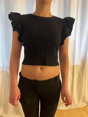 Svart topp - En svart magtröja topp med volang armar. Perfekt för lite mer uppklädd vardag. Nästan aldrig använd. Hör av er vid fler frågor 