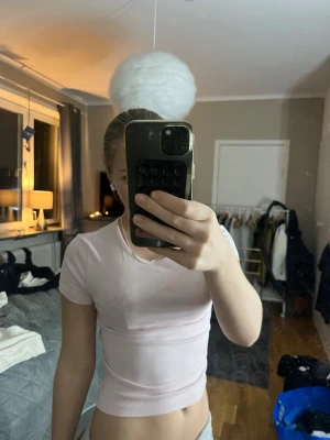 Ljusrosa croppad t-shirt - Säljer en ljusrosa croppad t-shirt med tight passform och korta ärmar. Perfekt till jeans eller kjol för en enkel och fräsch look. Materialet känns mjukt och stretchigt, vilket gör den bekväm att bära hela dagen.