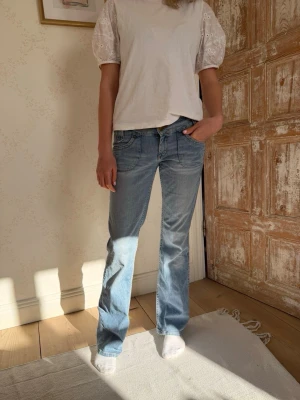 Lee Ljusblå lågmidjade bootcut jeans med fickdetaljer - Säljer ett par ljusblå lowwaist bootcut jeans med snygga fickdetaljer bak och klassisk femficksmodell från Lee. Jeansen har låg midja och är tillverkade i ett mjukt denimtyg med lätt tvättad look. 