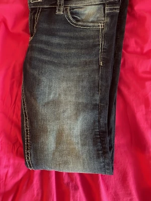 Lågmidjade jeans - Snygga mörkblå jeans med slitningar och tydliga vita kontrastsömmar. Klassisk femficksmodell och normal midja. Jeansen har en tvättad look och raka ben. Perfekta för en avslappnad stil. Uppsydda!!