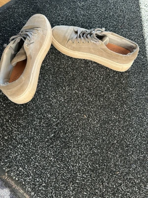 Beige sneakers i mocka - Snygga beige sneakers i mocka med klassisk låg profil och tjock sula. Skorna har matchande beige snörning och en enkel, stilren design som passar till det mesta. Perfekta för dig som gillar en clean och avslappnad look.