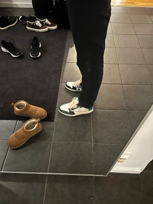 Nike Air Jordan 1 Retro High OG blå/vit - Säljer ett par Nike Air Jordan 1 Retro High OG sneakers i blått, vitt och svart. Klassisk high-top modell med vita snören och detaljer i läder. Perfekta för dig som vill ha en ikonisk och stilren sneaker med streetwear-vibe.