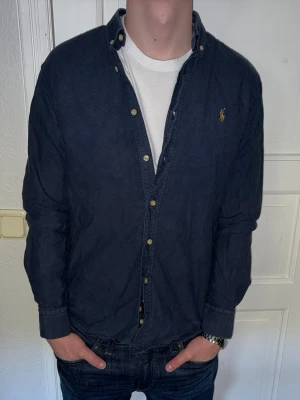 Mörkblå skjorta från Ralph Lauren - Mörkblå skjorta från Ralph Lauren i storlek M. Fint skick till ett bra pris. Nypris: 1995kr. Mitt pris: 299kr. Däremot är ett av knapphålen lite slitna. Ingenting som syns vid användning. Därav ett lite lägre pris. Vid frågor eller funderingar, tveka inte att höra av dig.