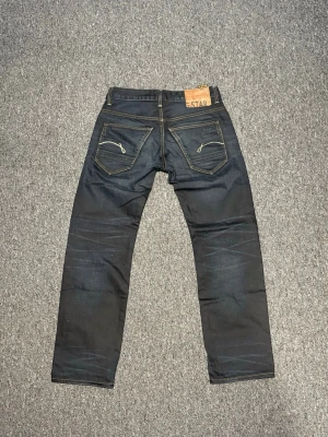 Mörkblå jeans från G-Star raw 29/30 - Säljer ett par mörkblå jeans från G-Star med raka ben. Jeansen har fem fickor, snygga detaljer på bakfickorna. Storleken på byxorna är 29/30 