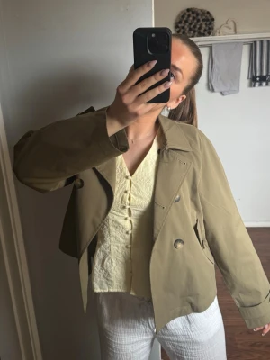 Militär grön trenchcoat - Säljer denna snygga gröna korta trenchcoat💚Supersnygg nu till våren och lätt att matcha med. Är i fint skick! 