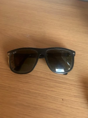  Ray-Ban boyfriend solglasögon - Klassiska svarta Boyfriend solglasögon från Ray-Ban med mörka glas och ikonisk fyrkantig form. Snygg metall-detalj vid bågens hörn och Ray-Ban-logga på sidan. Perfekta för att höja din stil under soliga dagar.