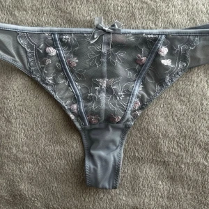 Grå spetsstring med blommönster - Olivia Strin. Ny pris 150kr.