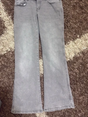 Gråa bootcut jeans från 157 - Säljer ett par gråa bootcut jeans från 157 och klassisk femficksdesign. Jeansen har utsvängda ben och dubbla knappar i midjan. Perfekta för dig som gillar en relaxed och trendig look. Har inte använt dom för att mamma köpte fel storlek och det har gått mer än 30 dgr