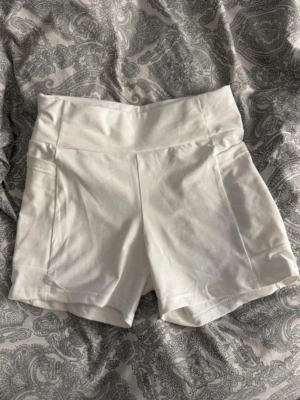 Vita högmidjade shorts i bomull - Snygga vita shorts med hög midja och bred linning. Tillverkade i mjuk bomull med en clean och enkel design utan synliga detaljer. Perfekta för varma dagar och passar till det mesta i garderobens.passar också perfekt till studenten eftersom dessa har fickor. 