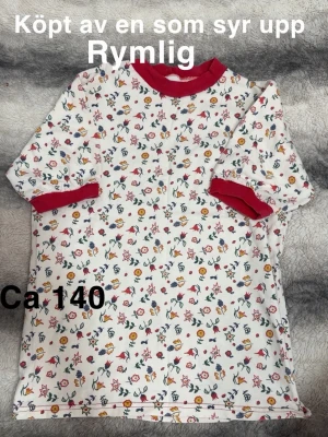 Blommig t-shirt med röda detaljer - Säljer en vit t-shirt med småblommigt mönster i flera färger och kontrasterande röda muddar vid hals och ärmslut. T-shirten har en rymlig passform och korta ärmar. Perfekt för dig som gillar färgglada och unika plagg!🌸 Köpt av en som syr själv. Minifläck. Rymlig. Storlek 140 