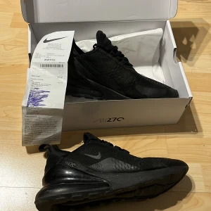 Nike Air Max 270 kvitto samt box - Snygga Nike Air Max 270 i helsvart färg. Skorna har en modern siluett med synlig Air Max-dämpning i hälen och ovandel i mesh för bra andningsförmåga. Perfekta för dig som gillar streetwear och sportig stil. Klassisk Nike-logga på sidan och bak. Med kvitto och box
