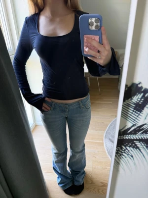 Mörkblå långärmad topp med vid ringning - En enkel och stilren mörkblå långärmad topp med vid, rundad ringning. Modellen är figurnära och passar perfekt till jeans eller kjol. Tunn och mjuk i materialet, vilket gör den skön att bära hela dagen.