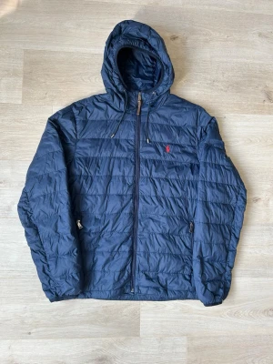 Blå Ralph Lauren Lätt Dunjacka Vårjacka Storlek L - Fin RL vårjacka i blå färg. Jackan är i mycket bra skick och sparsamt använd. |  Äkta som allt annat jag säljer! ✅ |  Storlek: L | Skick: Mycket Bra Skick - (Se sista bild) ett mycket litet hål vid botten av jackan | Färg: Blå | Märke: Ralph Lauren | Modell: Jacka |  Hör gärna av dig vid frågor så svarar jag så fort jag kan! 😁|   (SKU - 85)