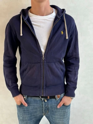 Ralph Lauren zip hoodie  - Säljer nu denna sjukt snygga Ralph Lauren Hoodien! Den har en liten defekt på armbågen som syns på andra bilden! Bara att höra av sig vid frågor eller funderingar! Modellen på bilden är 184cm och väger 80kg