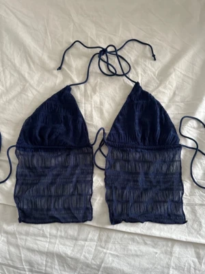 Marinblå topp - Trendig marinblå topp från shein med trekantsformade kupor och långa meshpaneler nedtill. Knytband i nacken och ryggen för justerbar passform. Materialet är en mix av polyester och syntet, vilket ger en lätt och bekväm känsla. 