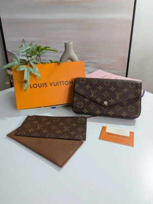 Iouis Vuitton pochette  - Detta är ett mångsidigt 3-i-1-set bestående av en elegant kuvertväska med tillhörande löstagbara insatser. Designen går i en klassisk brun färgskala med ett välkänt mönster av stiliserade blommor och geometriska symboler på en mörkbrun, texturerad canvasyta.