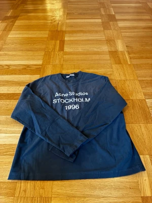 Mörkblå långärmad Acne Studios tröja - Pris kan sänkas vid snabb affär 🤩 Snygg mörkblå långärmad tröja från Acne Studios med vit text 'Acne Studios STOCKHOLM 1996' på bröstet. Klassisk passform och rund halsringning. Perfekt för dig som gillar stilrena och trendiga plagg.