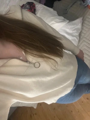 Beige stickad tröja med dragkedja - Mysig beige stickad tröja med halv dragkedja och ringdetalj i metall. Tröjan har långa ärmar och en avslappnad passform, perfekt att slänga på sig till jeans. Super fin, skön, normal passform och i storlek, fin i sommar men funkar helårs utmärkt också! Enkel och stilren design. Säljer även jeansen! 