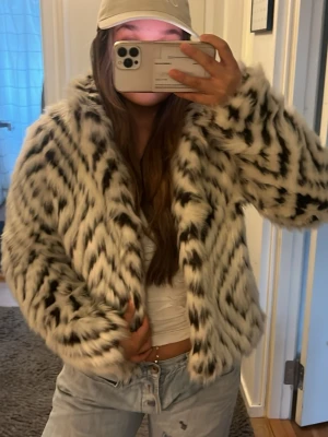 Vit och svart mönstrad pälsjacka - Säljer en fluffig pälsjacka med vit bas och svarta zigzag-mönster. Köpte jackan på Sellpy så den finns nog inte att få tag på någon annan stans. Säljs då jag har för många jackor💘