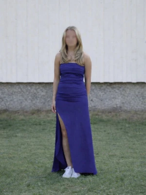 Balklänning - Snygg lång blå klänning med axelbandslös design och hög slits framtill. Klänningen är perfekt till balen, men även till ex bröllop. Tjejen på bilden är 160 cm lång och det är storlek xs🥰