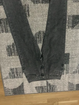 Grå tvättade raka jeans - Säljer ett par grå tvättade jeans med rak passform och klassisk femficksdesign. Jeansen har en snygg vintagekänsla och är tillverkade i bomull. Perfekta för en avslappnad och trendig stil.