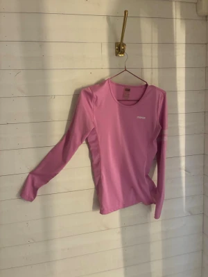 Rosa långärmad topp från Stronger - Snygg rosa långärmad topp från Stronger med rund halsringning och diskret logga på bröstet. Tillverkad i ett stretchigt och mjukt material som sitter skönt på kroppen. Perfekt för en avslappnad och sportig look.