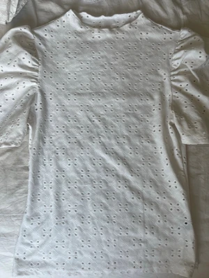 Vit blus med puffärm och broderi - Söt vit blus med puffiga korta ärmar och broderade hålmönster över hela plagget. Från shein, står ingen storlek i men skulle uppskatta xs-m då de är väldigt stretchigt material🩷
