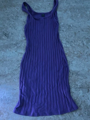 Lila ribbad ärmlös klänning - Säljer en lila ribbad klänning med smala axelband och figurnära passform. Klänningen är ärmlös och har en enkel, stilren design som passar perfekt till sommaren. Materialet känns mjukt och stretchigt.
