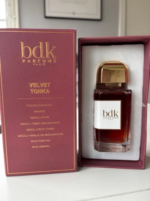 BDK Parfums Velvet Tonka EdP - Lyxig parfym från BDK Parfums, Velvet Tonka, i en elegant glasflaska med guldigt lock. Doften har inslag av apelsinblomma, mandel, ros, tobak, tonkaböna, vanilj, amyris och tränoter. Flaskan har en djup bärnstensfärgad vätska och stilren etikett.