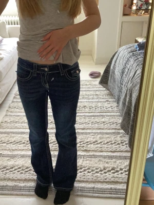 Mörkblå bootcut jeans med kontrastsömmar - Säljer ett par mörkblå bootcut jeans med vita sömmar. Jeansen har klassiska, snygga detaljer på bakfickorna och  utsvängda ben. 💞💕