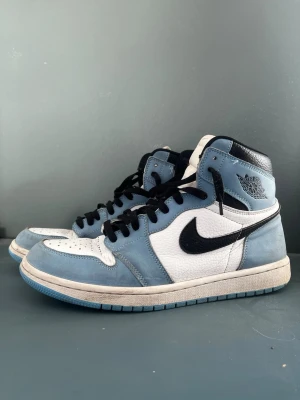 Jordan 1 university blue - Säljer nu dessa Jordan 1 university Blue ”og” då de inte riktigt är min stil längre. Skorna är strl 45, us11. Okej skick med lite skador på sulorna och insidan, original box följer med men i slitet skick.                Skicka bud ifall priset inte passar!
