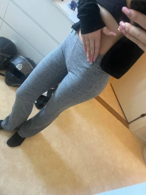 Grå ribbade mjukisbyxor - Säljer ett par grå ribbade mjukisbyxor med utsvängda ben och låg midja. Byxorna är stretchiga och superbekväma. Är i storlek xxs men ifall du är en eller två storlekar större funkar de också 