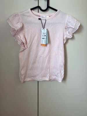 Ljusrosa topp med volangärmar Gina tricot - Supersöt ljusrosa topp från Gina tricot med volangärmar i spets. Toppen är helt oanvänd med prislappen kvar. Perfekt till våren. Ny pris 150 jag säljer för 70.