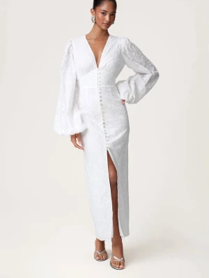 Adoore vit långklänning med spets och slits - Elegant vit långklänning med v-ringning, spetsdetaljer och knappar framtill. Klänningen har långa puffärmar och en slits som ger en snygg touch. Perfekt för dig som vill ha en stilren och romantisk look. Använd endast 1 gång! 34-36! Pris går att diskutera vid snabb affär!