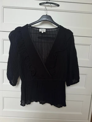 Svart romantisk blus med volang & puffärm - Superfin svart blus med romantiska detaljer. V-ringning, puffärmar och fina volanger som ger en väldigt feminin look. Resår i midjan gör att den sitter snyggt. Perfekt till jeans, kjol eller kostymbyxor – funkar både till vardag och fest. 🖤 Fint skick 🖤 Lätt och luftig 🖤 Trendig men tidlös Kan skickas snabbt. Kolla gärna mina andra annonser också ✨