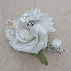 Hårklämma med blomma och fjäril - HELT OANVÄND. Superfin hårklåmma med stora vita blommor och en silverfärgad fjäril på toppen. Blommorna har en mjuk och fluffig look med grönt blad och små detaljer i gult. Perfekt för att ge en extra touch av elegans och somrig vibe.