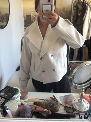 Beige kort rock från Kappahl - Beige kort kappa från Kappahl – strl S 🤍nypris 600 pris kan alltid diskuteras.  Superfin, stilren kappa i ljusbeige från Kappahl. Dubbelknäppning framtill och bred krage som ger en elegant och tidlös look. Perfekt till både vardag och mer uppklädda outfits.   Använd få gånger och i mycket fint skick. Storlek S – normal i storleken. Kort modell, mjuk och skön kvalitet.  Säljes då den tyvärr inte kommer till användning. ✨