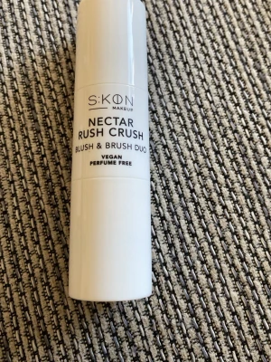 SKON Nectar Rush Crush Blush Peach - SKON Makeup Nectar Rush Crush Blush & Brush Duo i färgen Peach. Praktisk duo med både rouge och borste i ett, perfekt för att skapa en fräsch look. Vegansk och parfymfri formula i en smidig vit cylinderformad förpackning.