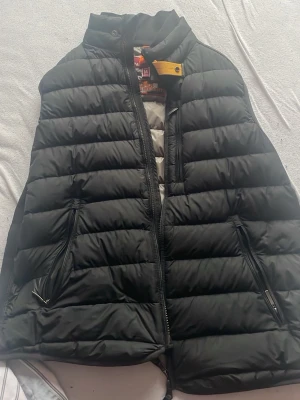 Parajumper väst - Snygg svart dunväst från Pjs i storlek M. Västen är superlätt, har två dragkedjeförsedda fickor och quiltad design. Perfekt för lager-på-lager och enkel att matcha med olika outfits. Insidan är grå och västen har hög krage.