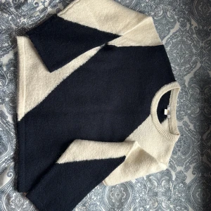 Svartvit stickad tröja med mönster - Säljer en snygg stickad tröja i mörk blå och vitt med grafiskt mönster. Tröjan har rund halsringning och långa ärmar. Materialet är mjukt och fluffigt. Passar dig som gillar en modern och stilren look. 