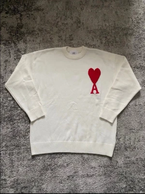 Vit Ami Paris tröja - Riktigt fet Ami tröja i vitt med röd logga på bröstet. Tröjan är storlek S och skicket är mycket bra, utan  några defekter. Perfekt för dig som söker en stilren look med en gnutta elegans. Hör gärna av dig vid minsta fundering så löser vi nåt!