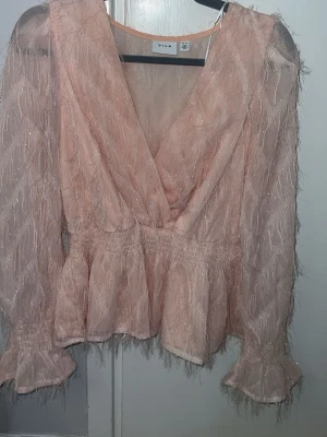 Rosa blus - Supersöt ljusrosa blus från Vila med fluffig textur och glittriga detaljer. Djup v-ringning, markerad midja. 