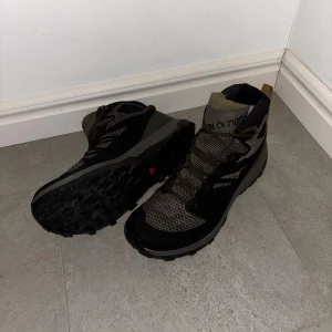Salomon svarta hikingkängor - Original pris 1899kr. Säljer ett par svarta och grå hikingkängor från Salomon. De har robust sula med grovt mönster för bra grepp, meshpaneler för ventilation och snörning hela vägen upp. Perfekta för utomhusaktiviteter och äventyr.