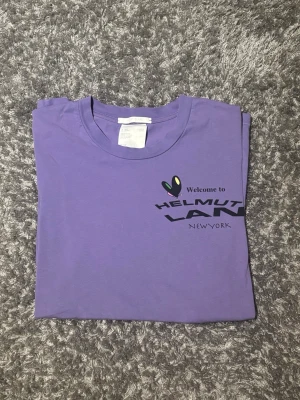 Helmut Lang t-shirt - Säljer en lila t-shirt från Helmut Lang i storlek M med riktigt feta och unika tryck både fram och bak. T-shirten passar perfekt för dig som gillar streetwear och unika prints.