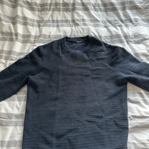 Mörkblå tröja från J.Lindeberg - Säljer en snygg mörkblå tröja från J.Lindeberg. Den har en cool textur och är perfekt för både vardag och lite finare tillfällen. Tröjan är i bra skick och har en normal passform. Perfekt för höst och vår!