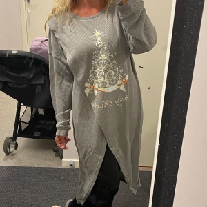 Grå långärmad jultröja med julgranstryck - Säljer en supermysig grå långärmad tröja med ett fint julgranstryck framtill. Perfekt för julmys och håller dig varm under vintern. Tröjan har en lös passform och är lite längre, vilket gör den extra bekväm. Perfekt för att mysa i hemma eller på julfesten! 🎄✨Helt ny