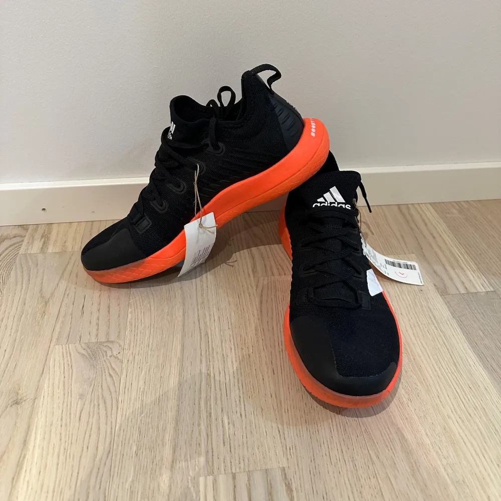 Säljer ett par snygga Adidas sneakers i svart och orange. De har en cool design med vita detaljer och en skön, dämpad sula. Perfekta för träning eller vardagsbruk. Skorna är i nytt skick och har aldrig använts. Storlek och passform är normal.. Skor.